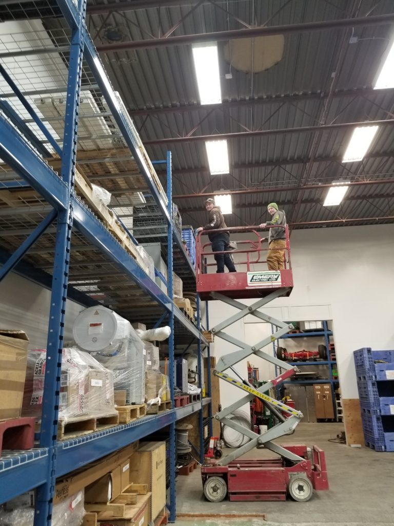 Two AWP trainees on a scissorlift in a warehouse